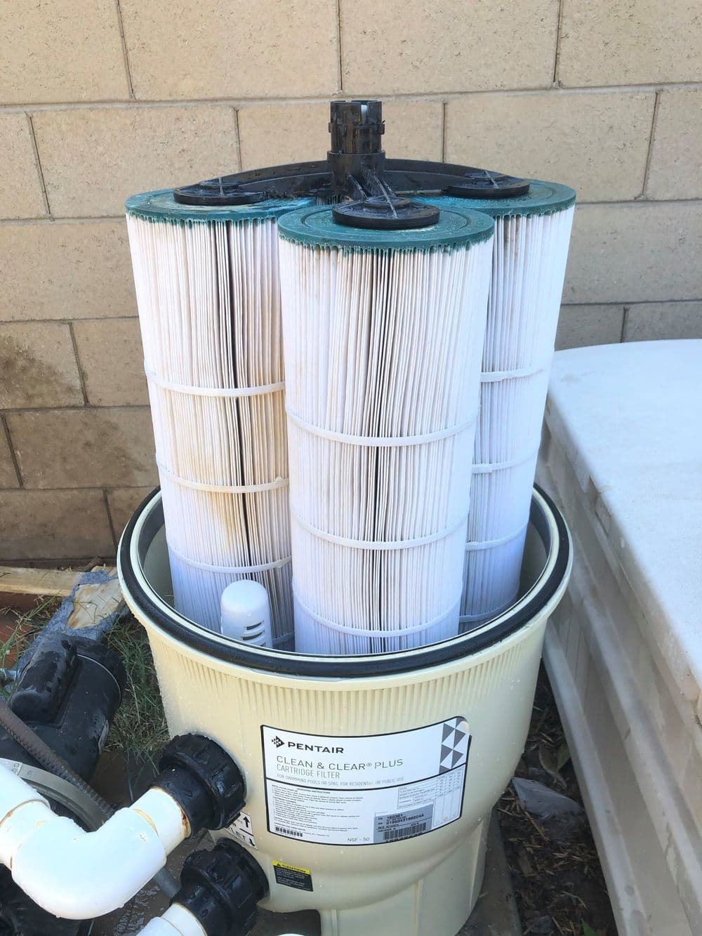 Pentair Clean & Clear Plus pool filter with three cartridge elements in a beige housing.
