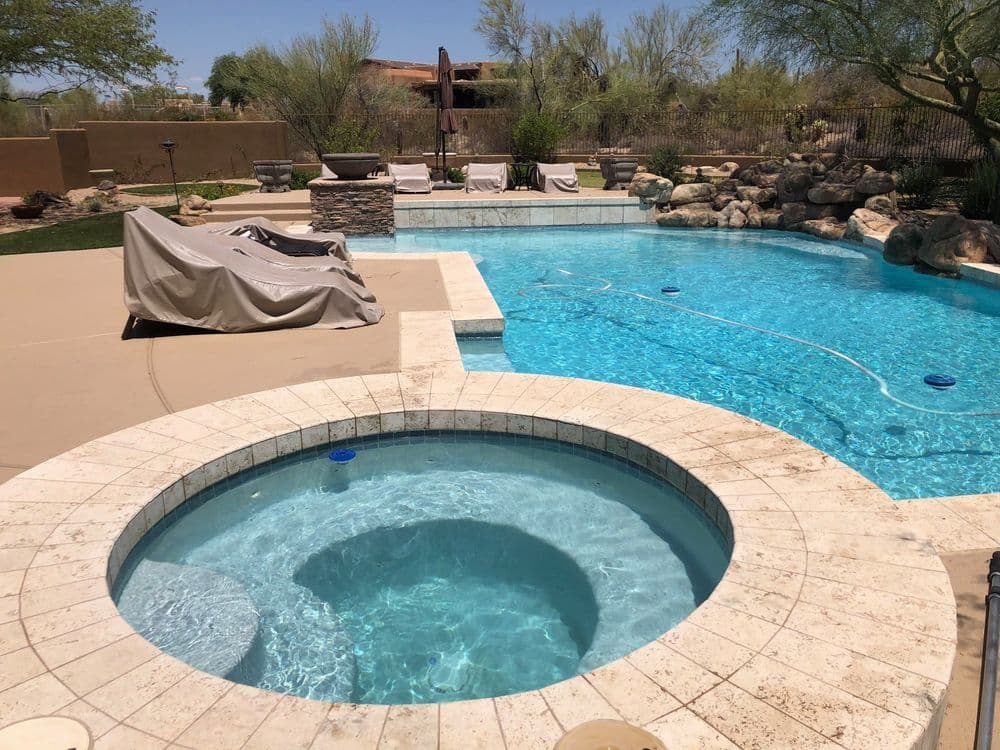 Luxury backyard with a swimming pool and spa surrounded by desert landscaping.