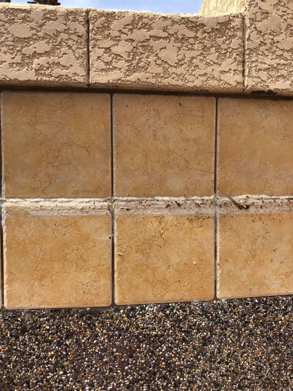 Close-up of textured beige wall tiles with a smooth darker base, showcasing craftsmanship details.